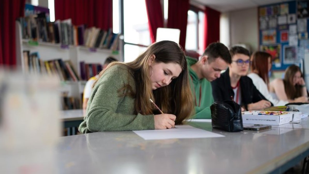 Students writing at desks in classroom