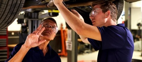 Apprentice mechanic working on a car